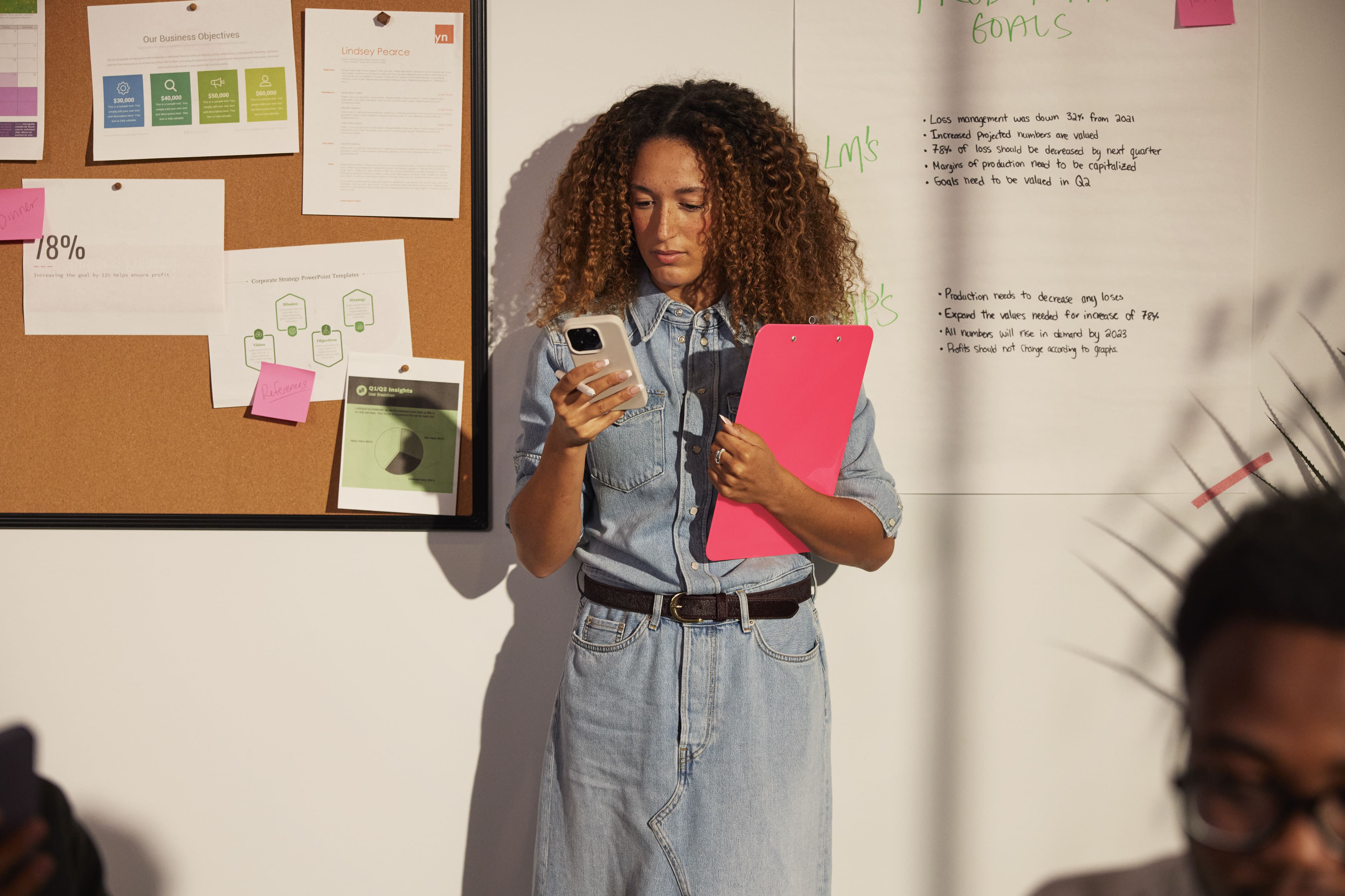Business strategist reviewing goals and performance notes beside a whiteboard and organized planning documents.