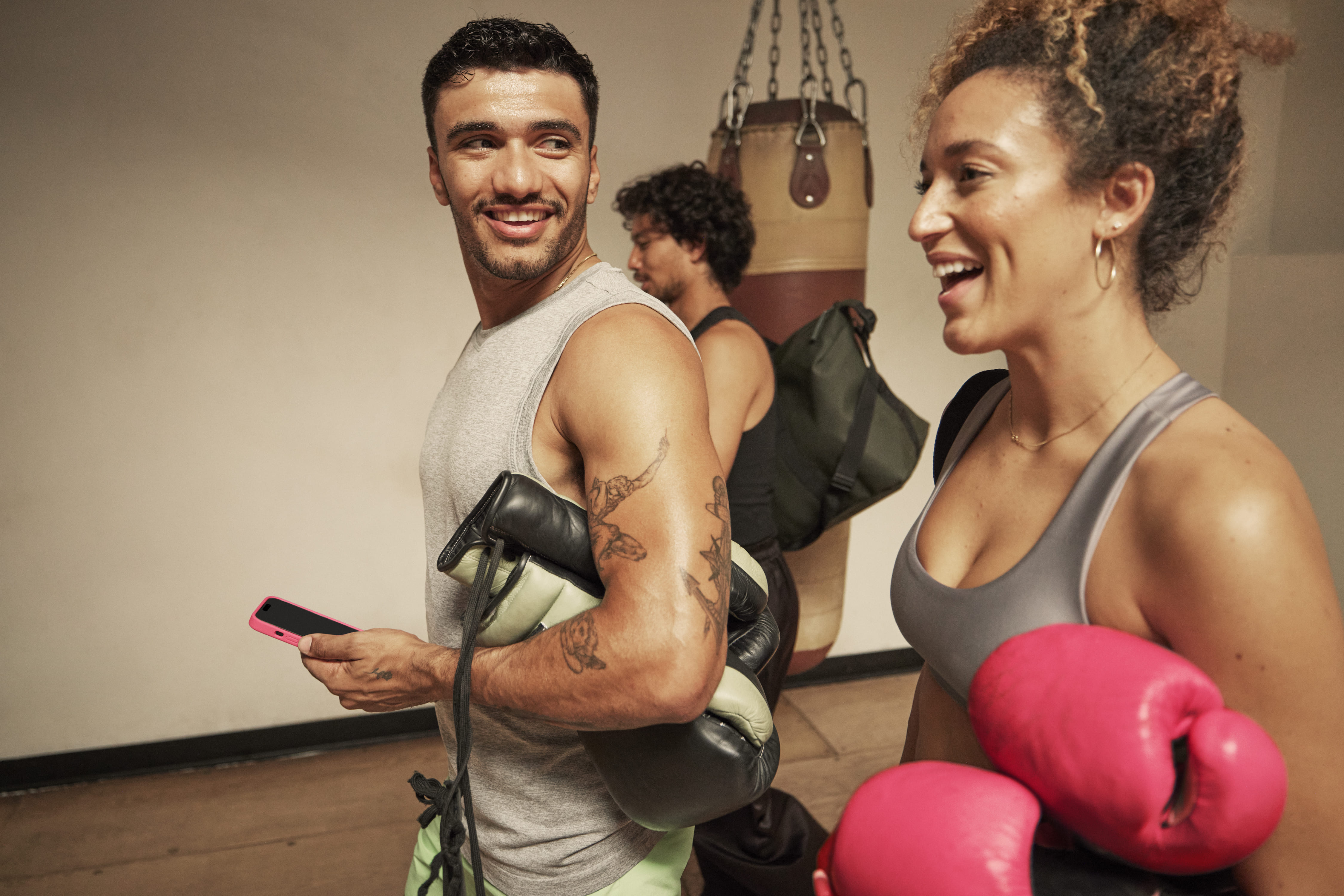 Diverse gym members smile together during a vibrant fitness session with equipment and colorful weights.